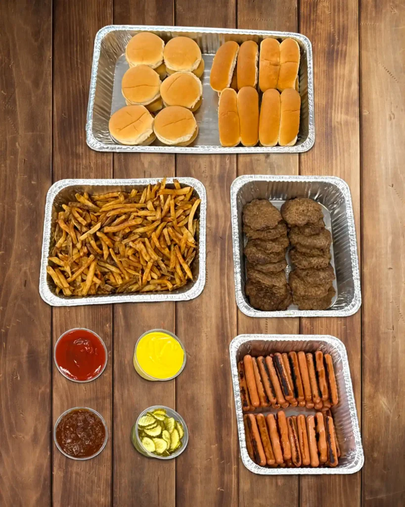 Small catering bar with buns, fries, burger patties, hot dogs, and condiments.